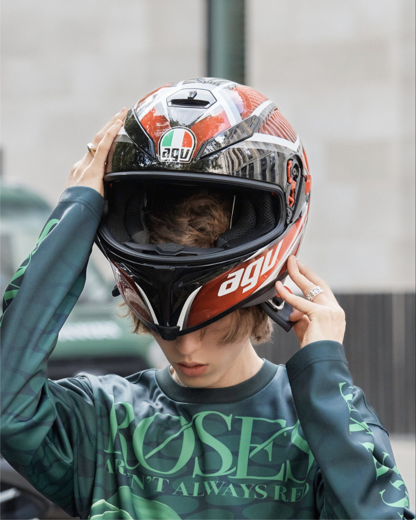 Model in AGV racing helmet and green graphic top reading 'Roses Aren't Always Red'
