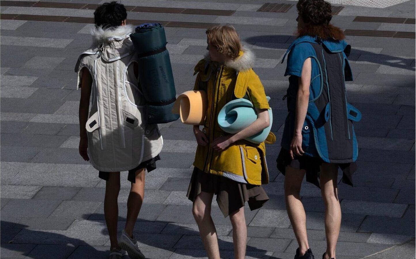 Three models walking from overhead, carrying camping gear