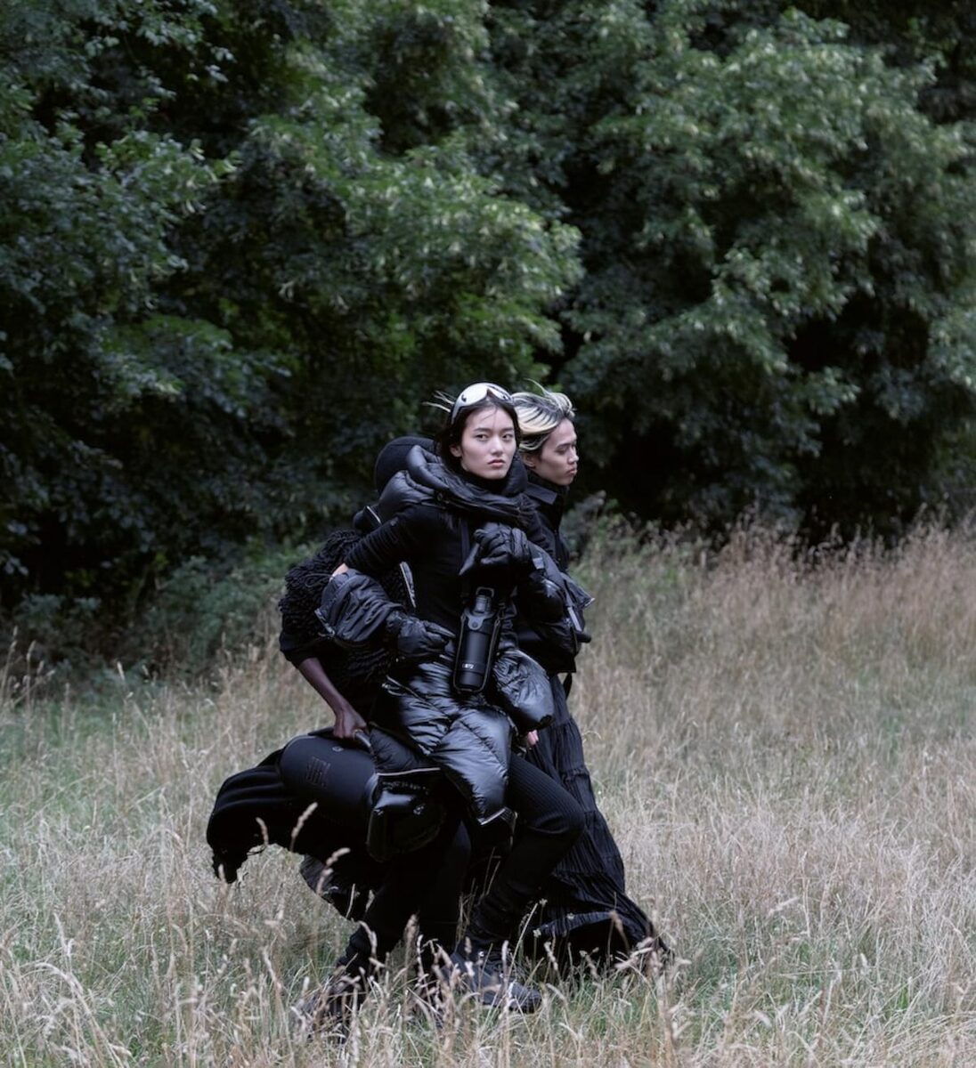 Two models in black Moncler outerwear moving through a field