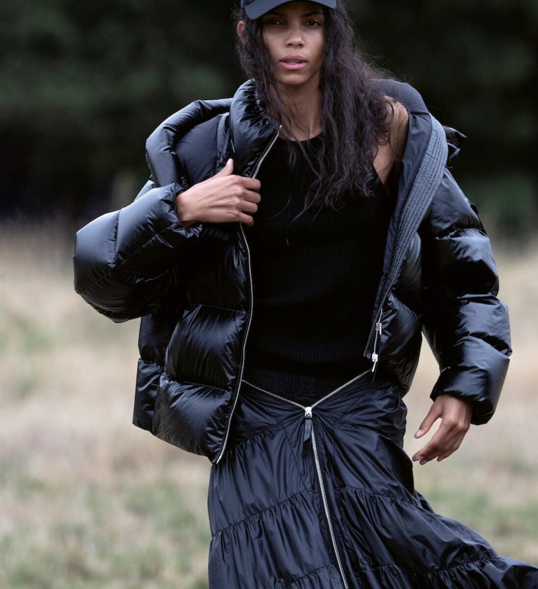 Model running in black Moncler puffer and cap
